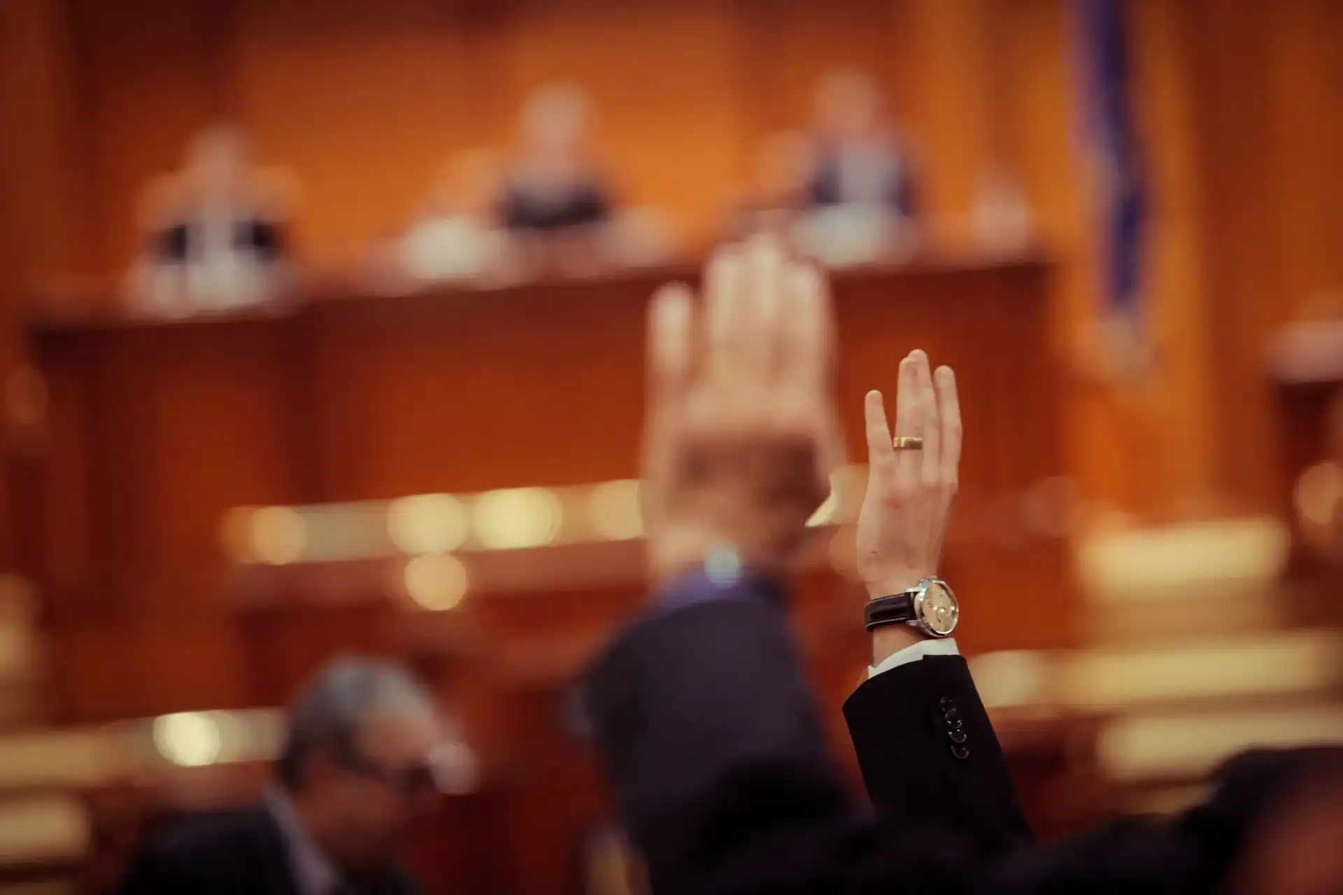 Zwei Hände werden in die Luft gestreckt, in einem Kongress-Saal.